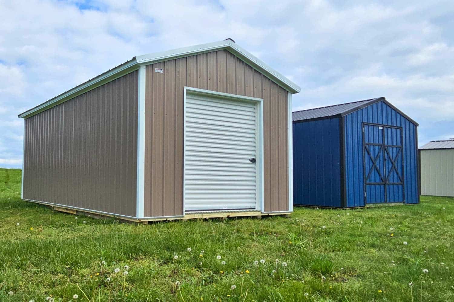 Beige and Blue metal sheds side by side in grassy field