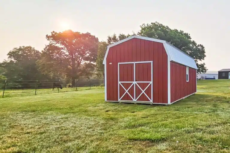 Red and white barn in field at sunset showcasing how to follow HOA shed rules and regulations