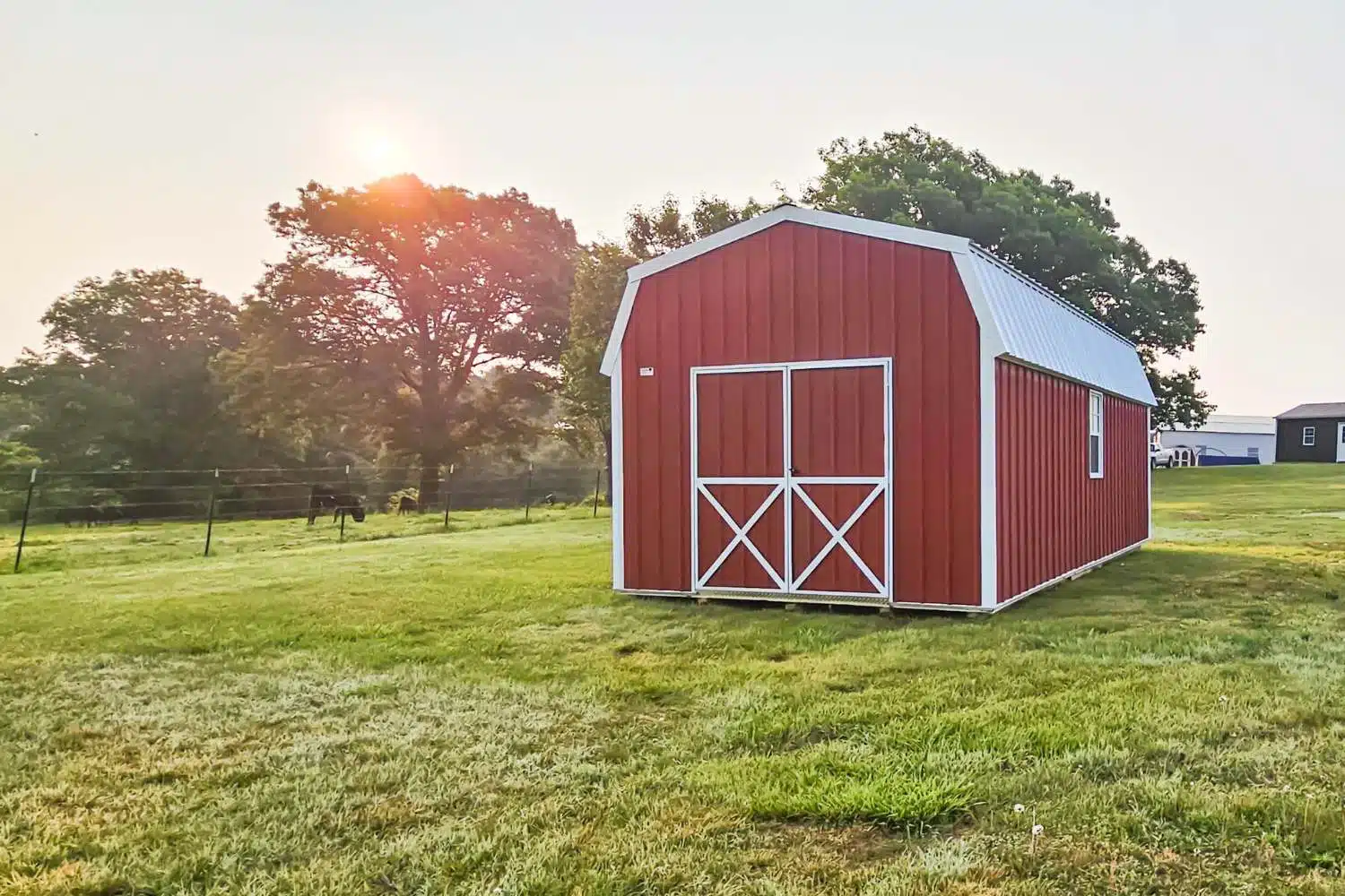 Red and white barn in field at sunset showcasing how to follow HOA shed rules and regulations